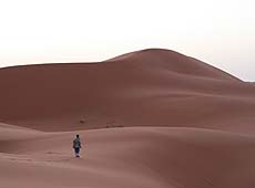 早朝のモロッコのサハラ砂漠を歩く少年