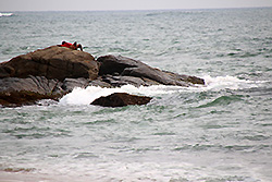 スリランカの世界遺産ゴールの海の岩場で休む男性